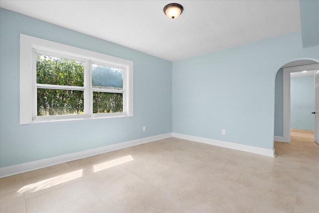 spare room with arched walkways and baseboards