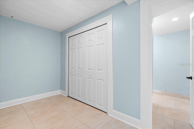 unfurnished bedroom with baseboards, a closet, and light tile patterned floors