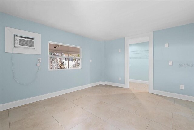 spare room with baseboards, a wall mounted AC, and light tile patterned flooring