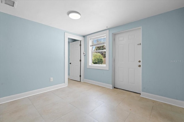 tiled empty room featuring baseboards and visible vents