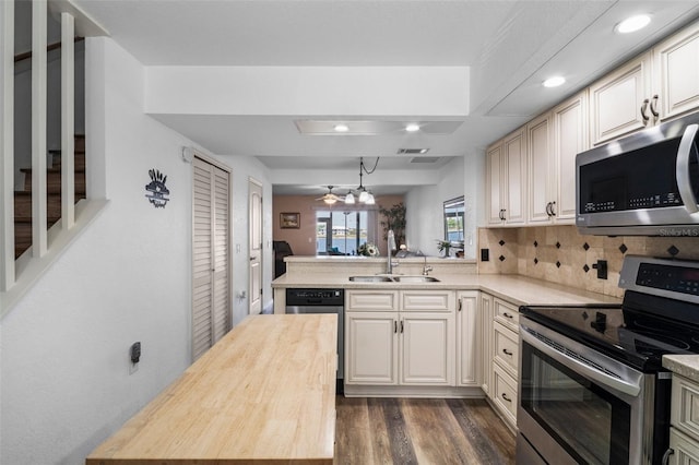 26290 Rampart Blvd Unit D, Punta Gorda, FL 33983 - kitchen featuring appliances with stainless steel finishes, a peninsula, wooden counters, backsplash, and dark wood-type flooring