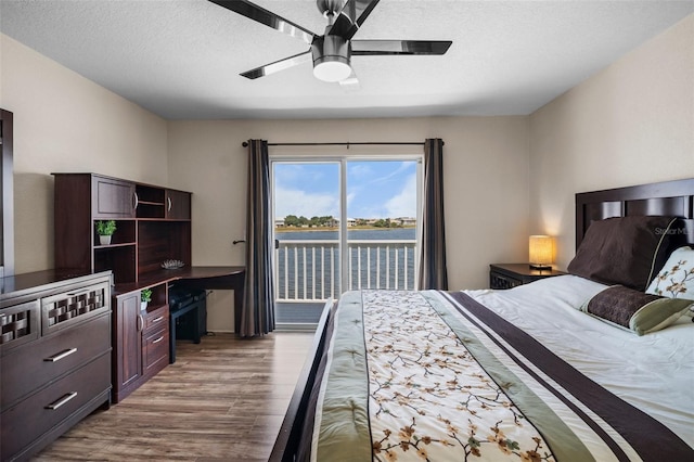 26290 Rampart Blvd Unit D, Punta Gorda, FL 33983 - bedroom with wood finished floors, access to exterior, ceiling fan, a textured ceiling, and a water view