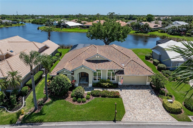 view of front of home featuring driveway, a tiled roof, a water view, and a garage