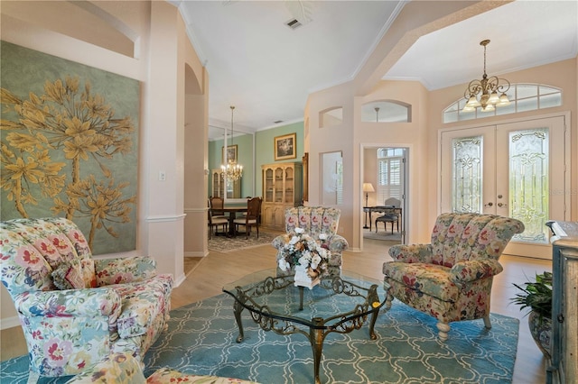 living room with crown molding, a notable chandelier, wood finished floors, and visible vents