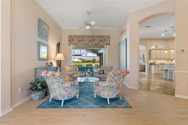 sitting room featuring crown molding, arched walkways, ceiling fan, and wood finished floors