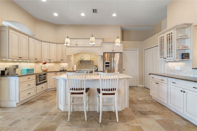 kitchen featuring tasteful backsplash, glass insert cabinets, stainless steel fridge with ice dispenser, stone tile floors, and a center island with sink