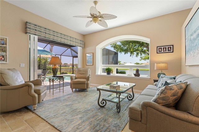 living area featuring a wealth of natural light, stone tile flooring, and ceiling fan