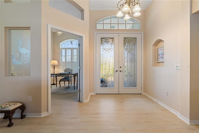 entryway featuring ornamental molding, a chandelier, french doors, and light wood-type flooring