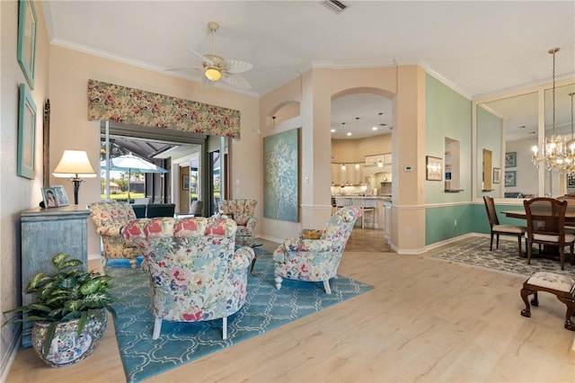 interior space featuring ornamental molding, wood finished floors, and ceiling fan with notable chandelier