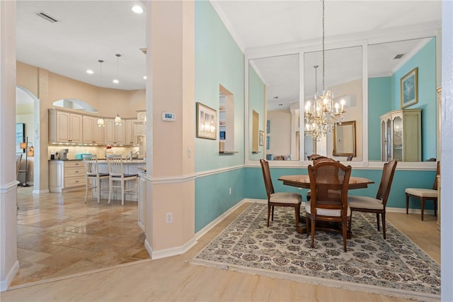 dining area featuring an inviting chandelier, visible vents, baseboards, ornamental molding, and arched walkways