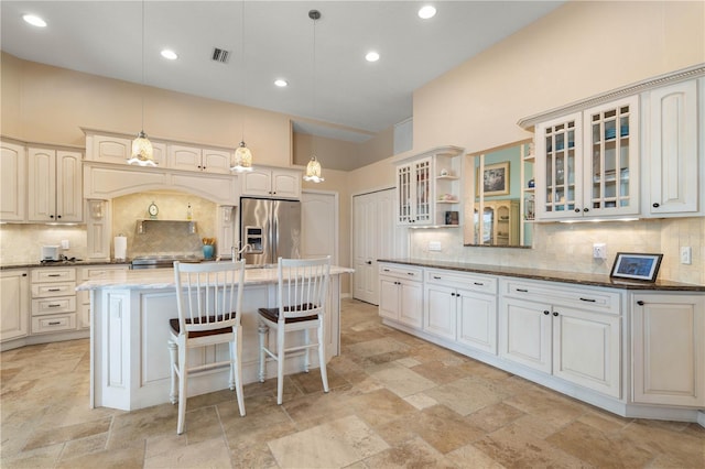 kitchen with stone tile flooring, tasteful backsplash, and stainless steel fridge with ice dispenser