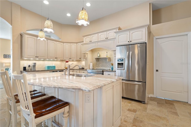 kitchen featuring tasteful backsplash, arched walkways, stainless steel appliances, a sink, and pendant lighting