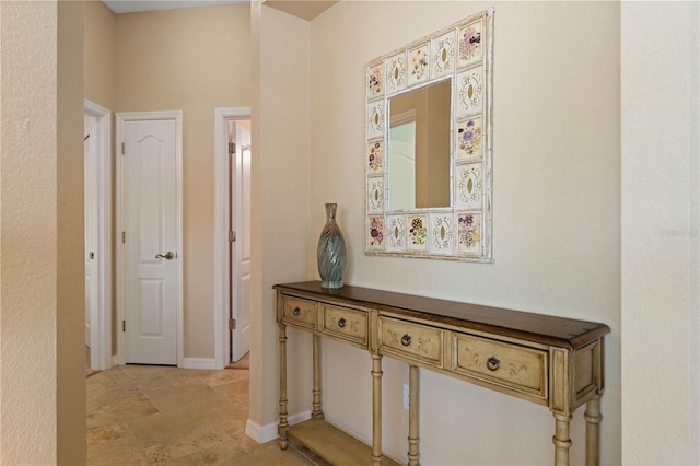 hall featuring baseboards and stone finish floor