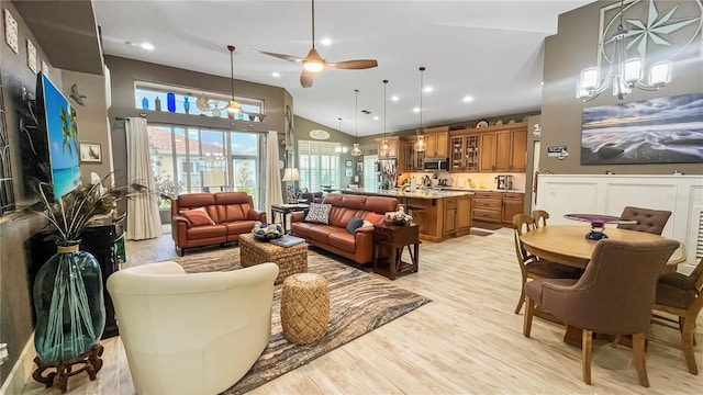 living room with high vaulted ceiling, recessed lighting, light wood finished floors, and ceiling fan with notable chandelier