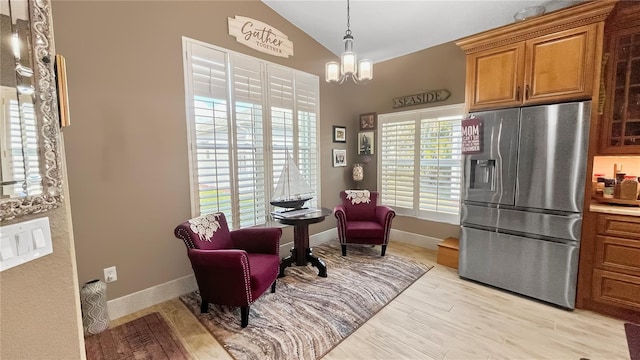 living area with a chandelier, vaulted ceiling, baseboards, and light wood-style flooring