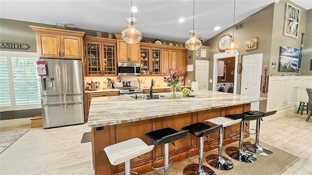 kitchen with stainless steel appliances, light wood-style flooring, a kitchen bar, visible vents, and independent washer and dryer
