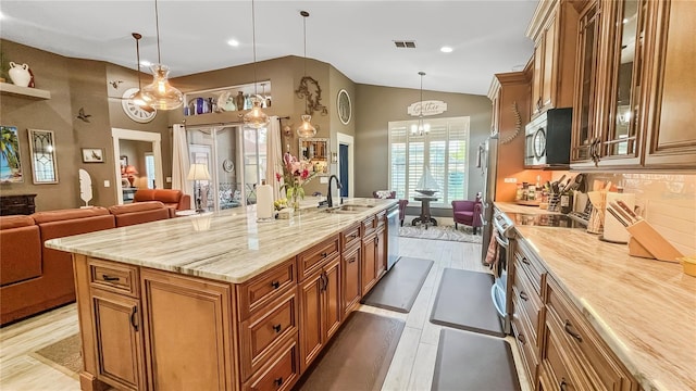 kitchen featuring visible vents, a sink, glass insert cabinets, brown cabinetry, and appliances with stainless steel finishes