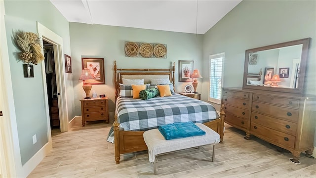 bedroom with baseboards, light wood-type flooring, and high vaulted ceiling