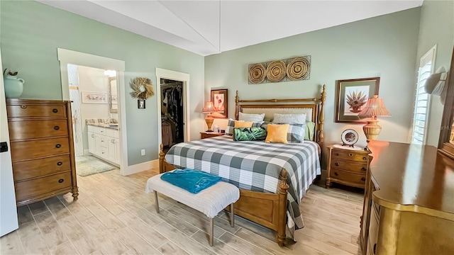 bedroom with a spacious closet, light wood-style floors, ensuite bathroom, and a closet