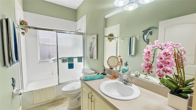 full bathroom with wood finished floors, toilet, vanity, and bath / shower combo with glass door