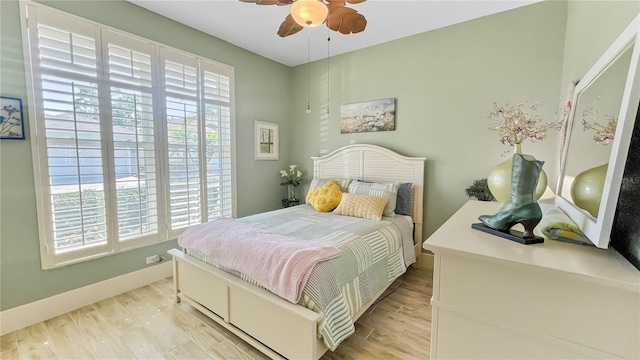 bedroom with ceiling fan, baseboards, and light wood-style flooring