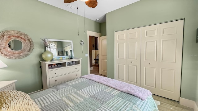 bedroom featuring light wood-style flooring, visible vents, a closet, and a ceiling fan