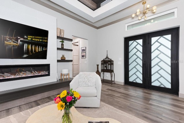 interior space with a glass covered fireplace, baseboards, an inviting chandelier, and wood finished floors