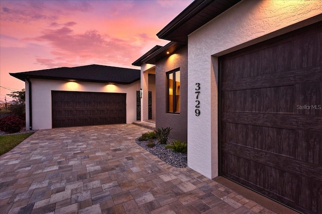garage at dusk featuring driveway