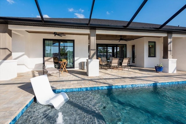 rear view of house with a ceiling fan, an outdoor pool, a patio, outdoor dining space, and stucco siding