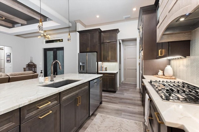 kitchen with decorative backsplash, dark brown cabinetry, a sink, custom exhaust hood, and stainless steel appliances