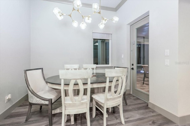 dining space featuring an inviting chandelier, baseboards, and wood finished floors