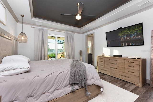 bedroom featuring a ceiling fan, visible vents, access to exterior, wood finished floors, and a raised ceiling