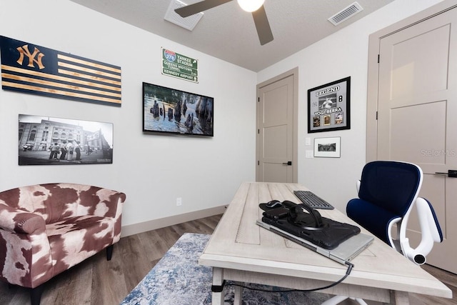 office area featuring a ceiling fan, baseboards, visible vents, and wood finished floors