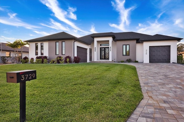 prairie-style house featuring stucco siding, driveway, a front yard, and a garage