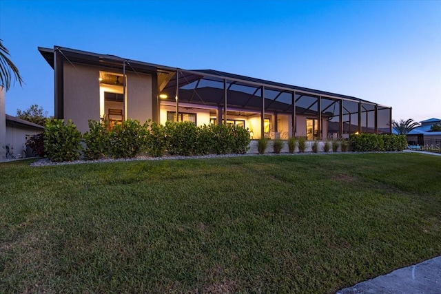 back of property with a lawn, a lanai, and stucco siding