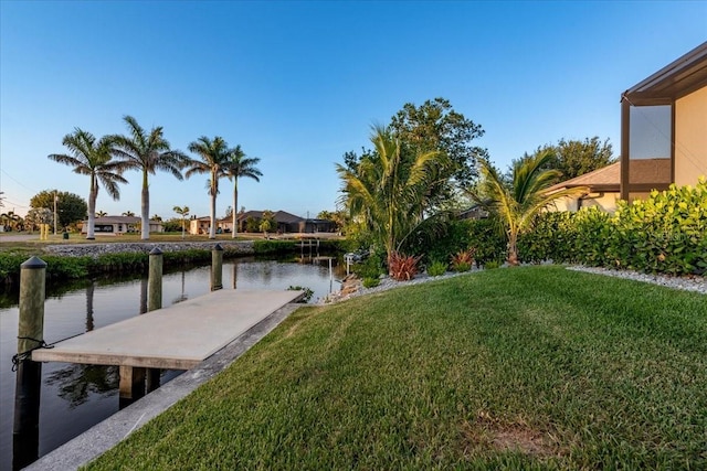 view of dock featuring a lawn and a water view
