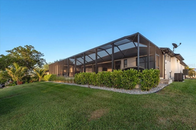back of house with a lawn, glass enclosure, and central air condition unit