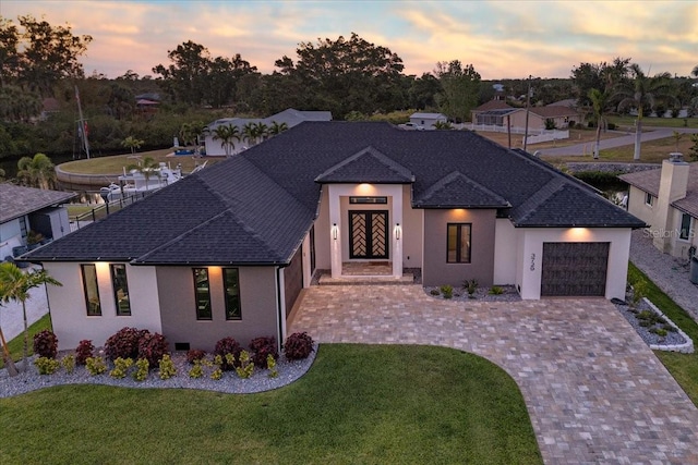 view of front of home with a lawn, stucco siding, driveway, and a garage