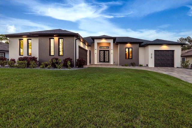 prairie-style house with a garage, stucco siding, driveway, and a front yard