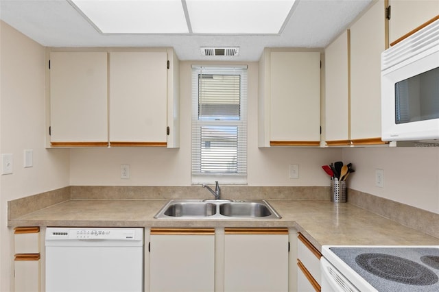 kitchen with a sink, light countertops, white appliances, and visible vents