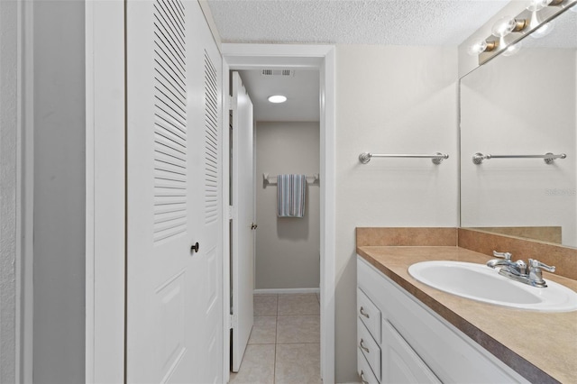 bathroom with visible vents, vanity, baseboards, a textured ceiling, and tile patterned floors