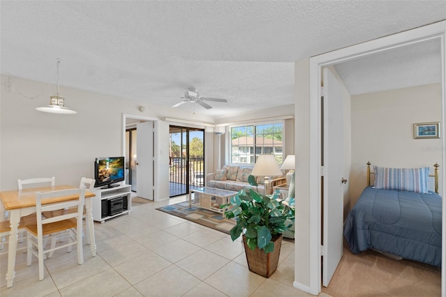 living area with light tile patterned floors, a ceiling fan, and a textured ceiling