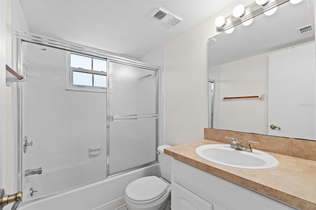 bathroom with vanity, toilet, shower / bath combination with glass door, and visible vents