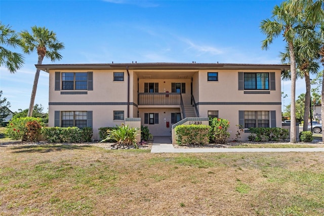 view of front of house with stairs, stucco siding, and a front yard