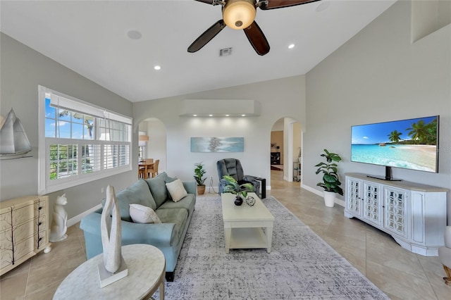 living area featuring arched walkways, visible vents, a ceiling fan, and vaulted ceiling