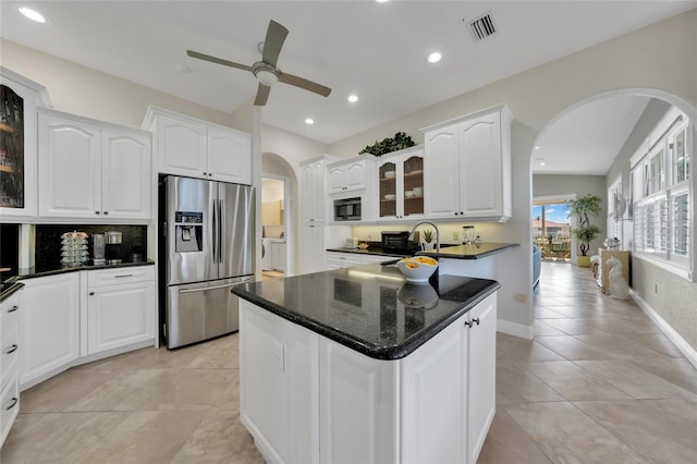 kitchen featuring glass insert cabinets, stainless steel refrigerator with ice dispenser, visible vents, ceiling fan, and arched walkways