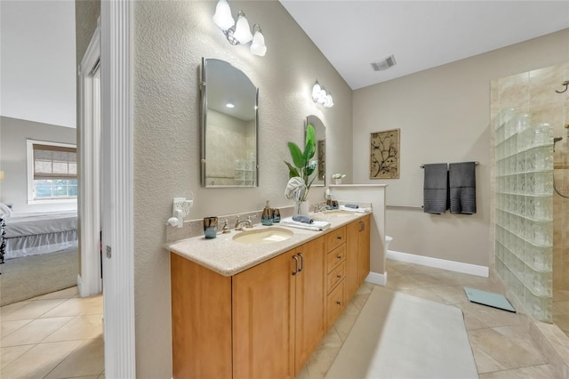 ensuite bathroom featuring a sink, ensuite bathroom, visible vents, a textured wall, and double vanity