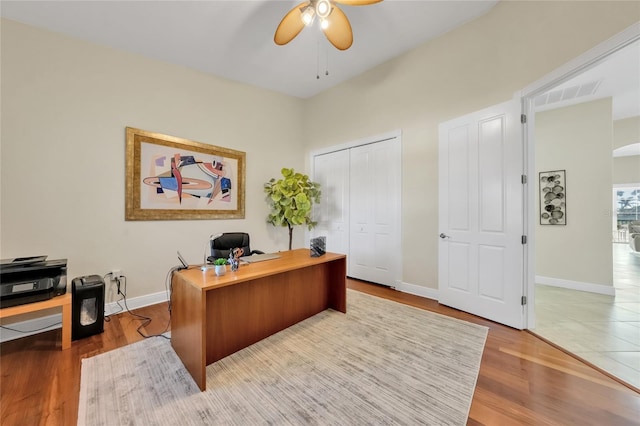 office space with baseboards, visible vents, ceiling fan, and wood finished floors