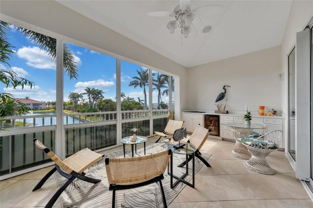 sunroom / solarium featuring a ceiling fan, lofted ceiling, area for grilling, beverage cooler, and tile patterned floors