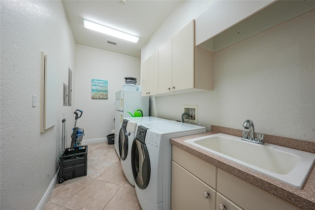 laundry area featuring visible vents, a sink, washing machine and clothes dryer, cabinet space, and a textured wall